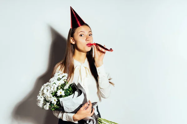 Una joven celebra algo, en una gorra roja y con un gran ramo de flores blancas — Foto de Stock