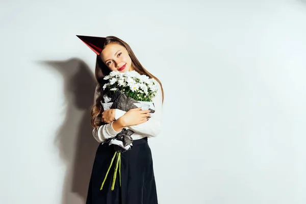 Una joven celebra algo, en una gorra roja y con un gran ramo de flores blancas — Foto de Stock