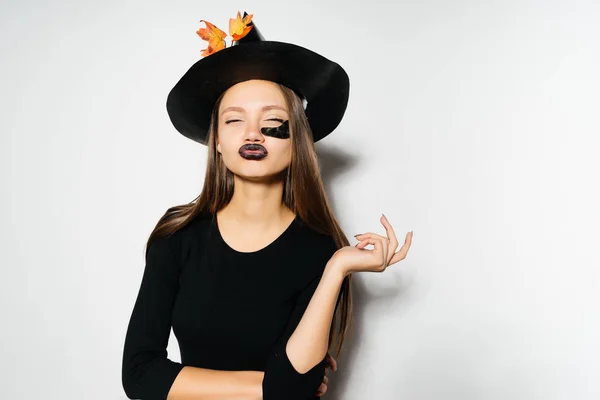 Una joven gótica en la imagen de una bruja en Halloween, toma una mano por la cara y jura — Foto de Stock