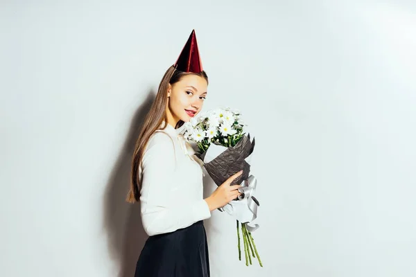 Uma jovem em um chapéu festivo vermelho mantém um grande buquê de flores brancas — Fotografia de Stock