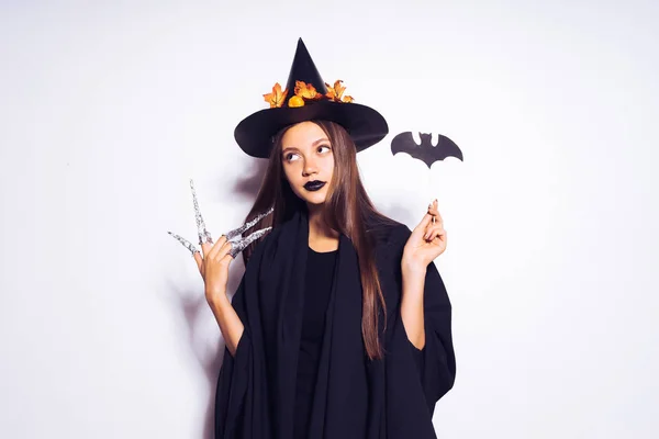 Gothic meisje in het beeld van een heks in halloween, houdt in haar hand een tekening van een vleermuis — Stockfoto