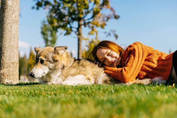 Una joven camina con su gran perro en el parque, se encuentra en el césped verde — Foto de Stock