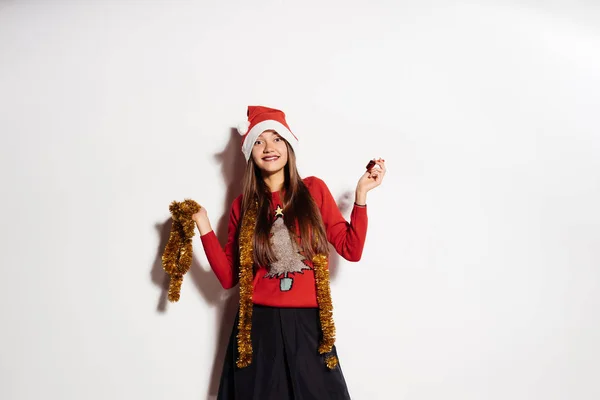 Junges lustiges Mädchen feiert Neujahr und Weihnachten, mit roter Mütze und goldenem Lametta — Stockfoto
