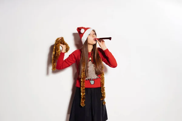 Joven chica divertida celebra Año Nuevo y Navidad, en una gorra roja y oropel de oro — Foto de Stock