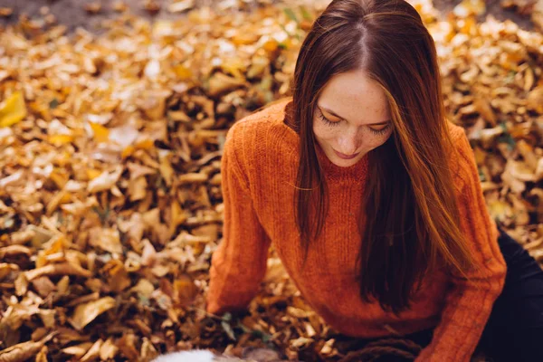 Rudowłosa dziewczyna bawi się z psem w stosie liści jesienią upadły — Zdjęcie stockowe