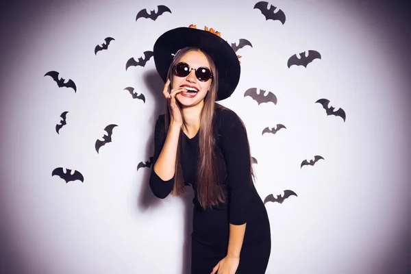 Mladá usměvavá sexy dívka v obrázku čarodějnice v halloween, na zdi kresby černé netopýry — Stock fotografie