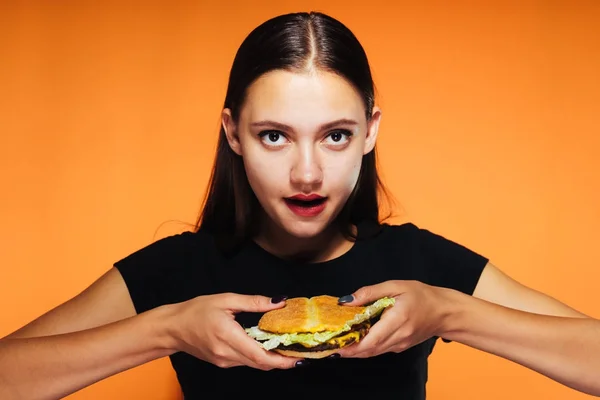 Молода дівчина хоче схуднути, але їсть шкідливий гамбургер — стокове фото