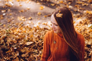 şık bir turuncu kazaklı genç bir kızıl saçlı kız altın düşen yapraklar oturur