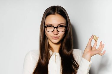 Gözlüklü genç modern iş kadını altın bitcoin elinde tutar.