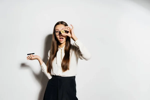 Jovem empresária detém um bitcoin ouro e um cartão bancário em suas mãos — Fotografia de Stock