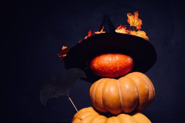 Cadılar Bayramı için bir ev dekorasyon için bir kompozisyon yalan sarı ve turuncu kabak, sarı yaprakları ile süslenmiş büyük kara cadı şapka