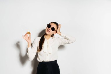 Altın bitcoin içinde güneş gözlüğü tutan genç iş kadını