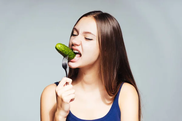 Una chica joven quiere perder peso así que come un pepino bajo en calorías — Foto de Stock