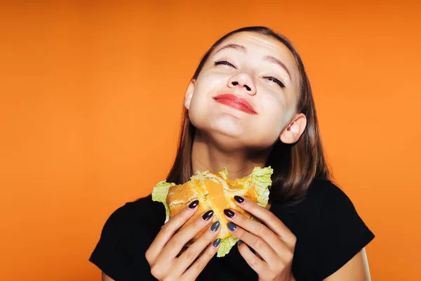 Голодна дівчина хоче схуднути, але з нетерпінням їсть шкідливий бургер — стокове фото