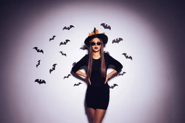 Gothic sexy dívka v obrázku čarodějnice slaví halloween, stojícím u zdi s výkresy, černé létající netopýři.. — Stock fotografie