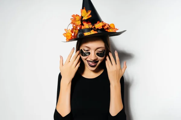 魔女という形で若いゴシック セクシーな女の子を祝うハロウィーン、黄金のカエデの葉で飾られた大きな帽子ブラック — ストック写真