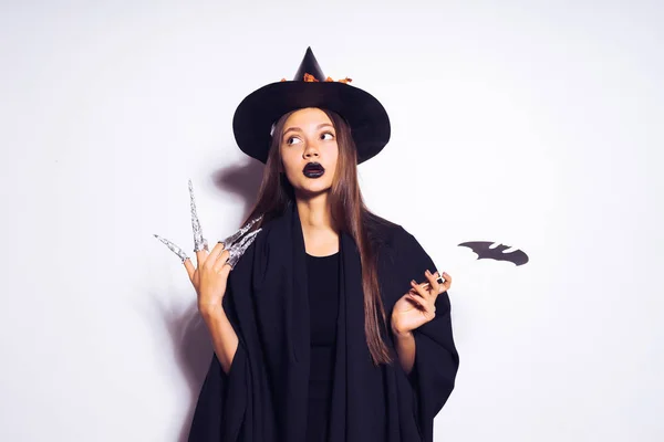 Mooi sexy gothic meisje in het beeld van een heks in halloween bedrijf een geschilderde vleermuis in haar handen — Stockfoto