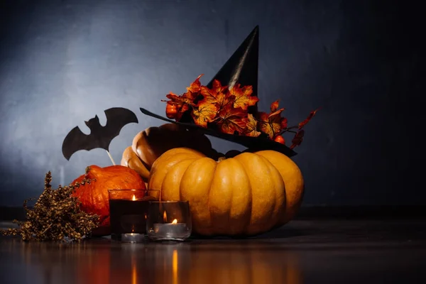 En komposition för att dekorera ett hus för halloween, gult och orange pumpor, brinnande doftljus och en svart häxa hatt — Stockfoto