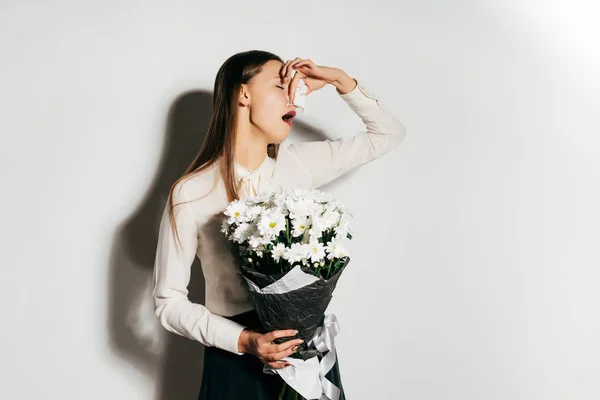 Una joven tiene un gran ramo de flores blancas en sus manos y estornuda porque es alérgica — Foto de Stock