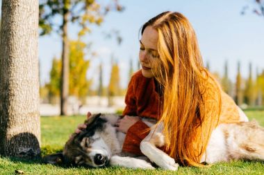 Kızıl saçlı güzel kız ile onun büyük köpek yeşil çimenlerin üzerinde oynuyor