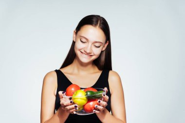 genç gülümseyen kız bir plaka ile yararlı sebze ve meyve tutan bir diyet oturuyor