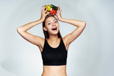 Siyah, çok, güzel bir kız gülümsüyor ve bir tabak sebze başını tutar. Güzel vücut, sağlıklı gıda.