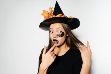 Uzun saçlı güzel bir cadı korkmuş ve uzağa baktı. Siyah bir takım elbise giymiş ve büyük cadı şapkası giyen bir kız. Cadı bir Cadılar Bayramı partisine gidiyordu.