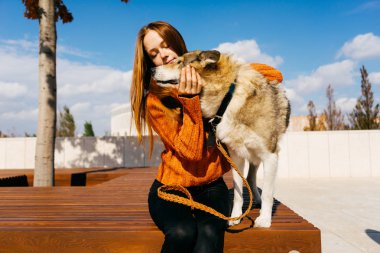 kız ile bir köpek yürüyüş. Turuncu bir kazak, bir kız köpeğini okşuyordu. Parkta yürümek. Sıcak bir sonbahar günü olduğunu.