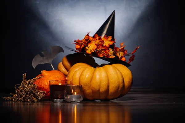 Att dekorera huset för Halloween, ljuga gula och orange pumpor, ljus bränna och en svart häxa hatt — Stockfoto