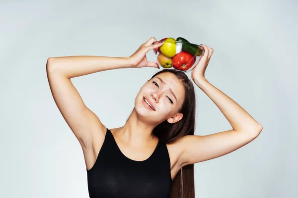 Krásná mladá dívka sportovní sleduje její postavu, drží desku s užitečné zeleniny a ovoce — Stock fotografie
