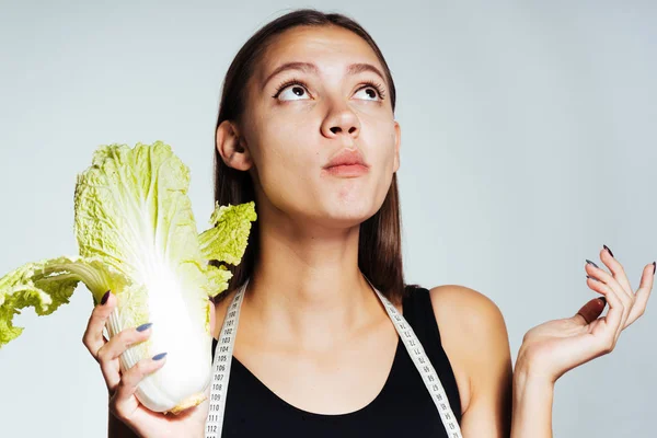 Giovane bella ragazza sportiva guarda la sua figura, mangia utile cavolo Pekinese — Foto Stock