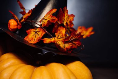 Cadılar Bayramı, siyah bir zemin üzerine altın sonbahar yaprakları ile süslenmiş siyah cadı şapka için büyük kabak