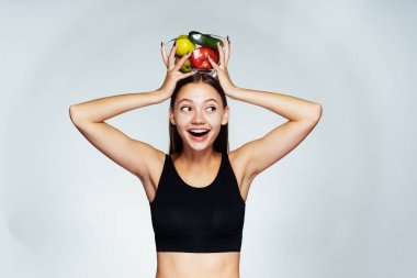 bir tabak sebze ile başını tutarak ve uzağa bakarak mutlu ince kız.