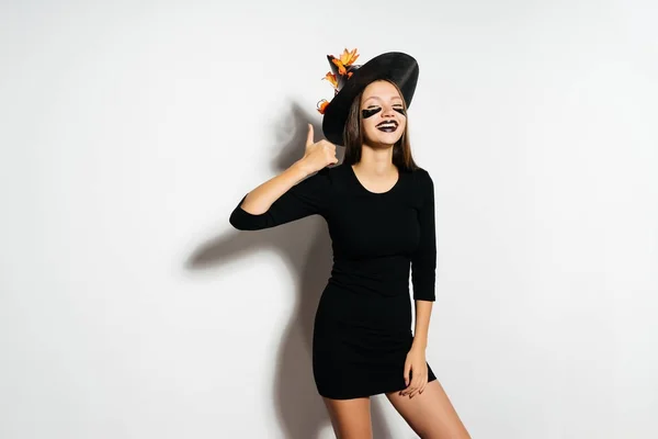 Meisje Halloween heks in een mooie zwarte jurk en het dragen van een hoed met herfst laat glimlachen. Het meisje op de Halloween party. Vakantie Halloween. — Stockfoto