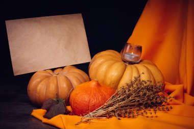 Siyah ve turuncu kumaşlarda Halloween pumpkins vardır ve bir mum yanıyor