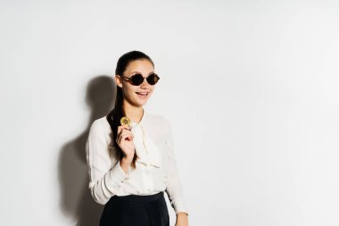 gülümseyen Kız bardaklarda ve altın sikke tutarak ve tarafına bakarak beyaz bir bluz, kripto para birimi, bitcoins, beyaz bir arka plan üzerinde izole