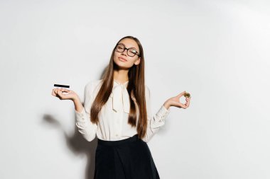 Beyaz bir güzel bluz ciddi bir kız bir banka kartı ve bir madeni para onun elinde tutar. Bitcoins, izole