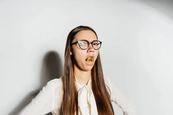 Uma jovem menina de óculos com a boca segura um bitcoin de ouro — Fotografia de Stock