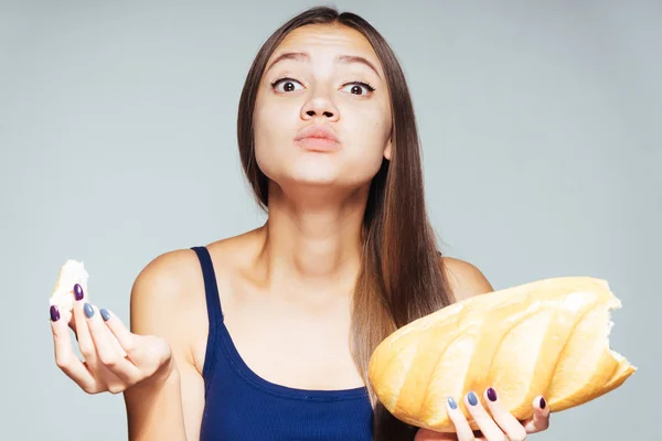 Kız bir ekmek yiyor. Aç kız kameraya doğru görünüyor ve bir somun onun elinde tutar. Beyaz arka plan üzerinde izole — Stok fotoğraf
