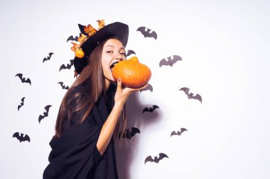 Uzun saçlı Halloween cadı balkabağına ısırmaya çalışır. Siyah bir takım elbise giymiş bir güzel kız bir partiye gidiyor. Yarasalar arka planı. Geniş Cadılar Bayramı partisi sanat tasarım