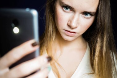 kızgın kız siyah bir arka plan üzerinde bir telefon elinde tutar.