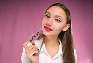 onun elleri sahte kirpik kız pembe bir arka plan üzerinde tutar