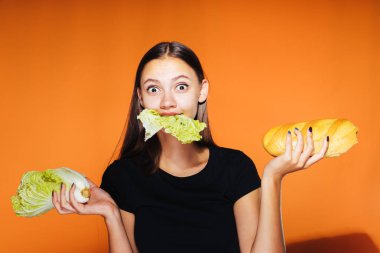 Kız bir lahana ve bir somun onun elinde tutar. Lahana, turuncu zemin üzerine izole çiğneme kız