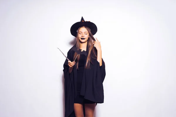 Una joven gótica sexy vestida con una bruja para Halloween, tiene en sus manos una varita mágica —  Fotos de Stock