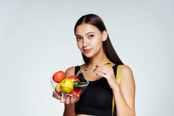 Unga glada smal flicka äta rätt, hålla en tallrik med användbar grönsaker och frukter — Stockfoto