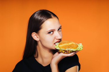 genç bir kız kilo vermek istiyor, ama sağlıksız bir yüksek kalorili hamburger yiyor