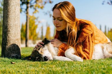 onun büyük köpek park, yeşil çim üzerinde yalan ile etkin bir kız yürüyor