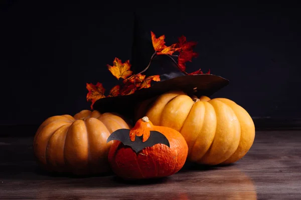 Samenstelling voor het verfraaien van een huis voor halloween, geel en oranje pompoenen, een grote zwarte heks hoed — Stockfoto