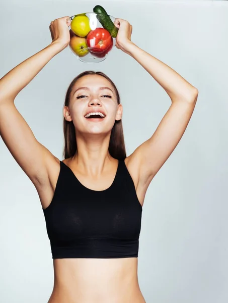 Unga glada smal flicka äta rätt, hålla en tallrik med användbar grönsaker och frukter — Stockfoto