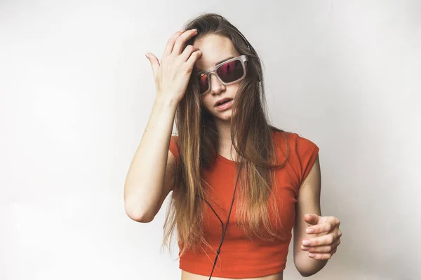 Mulher ouvindo em fones de ouvido pensando em um fundo branco — Fotografia de Stock